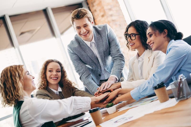 Усміхнена команда розміщує руки одна на одній, демонструючи співпрацю